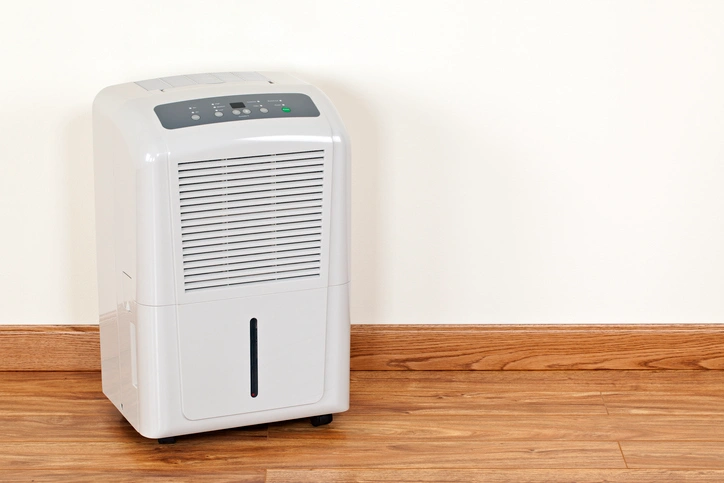 HVAC Dehumidifier In St. Louis Park, MN 1 A white air conditioner placed on a wooden floor, showcasing its sleek design and functionality in a room setting.